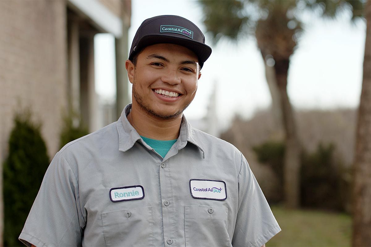 A man wearing a hat and a grey shirt with a name tag that says roberto