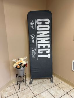 A sign that says connect is sitting in a corner next to a vase of flowers.