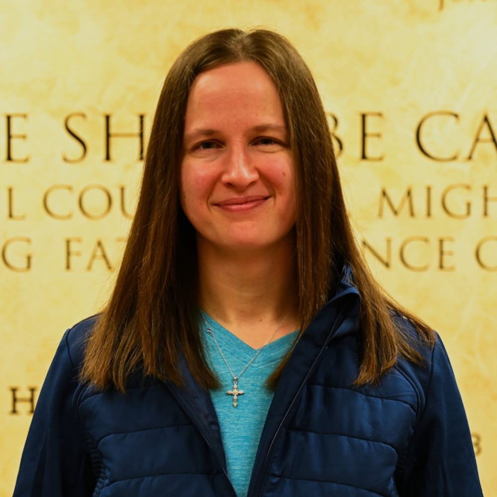 A woman wearing a blue jacket and a cross necklace
