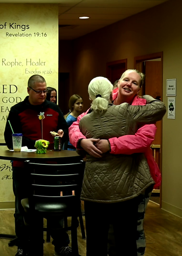 A woman in a pink jacket is hugging another woman