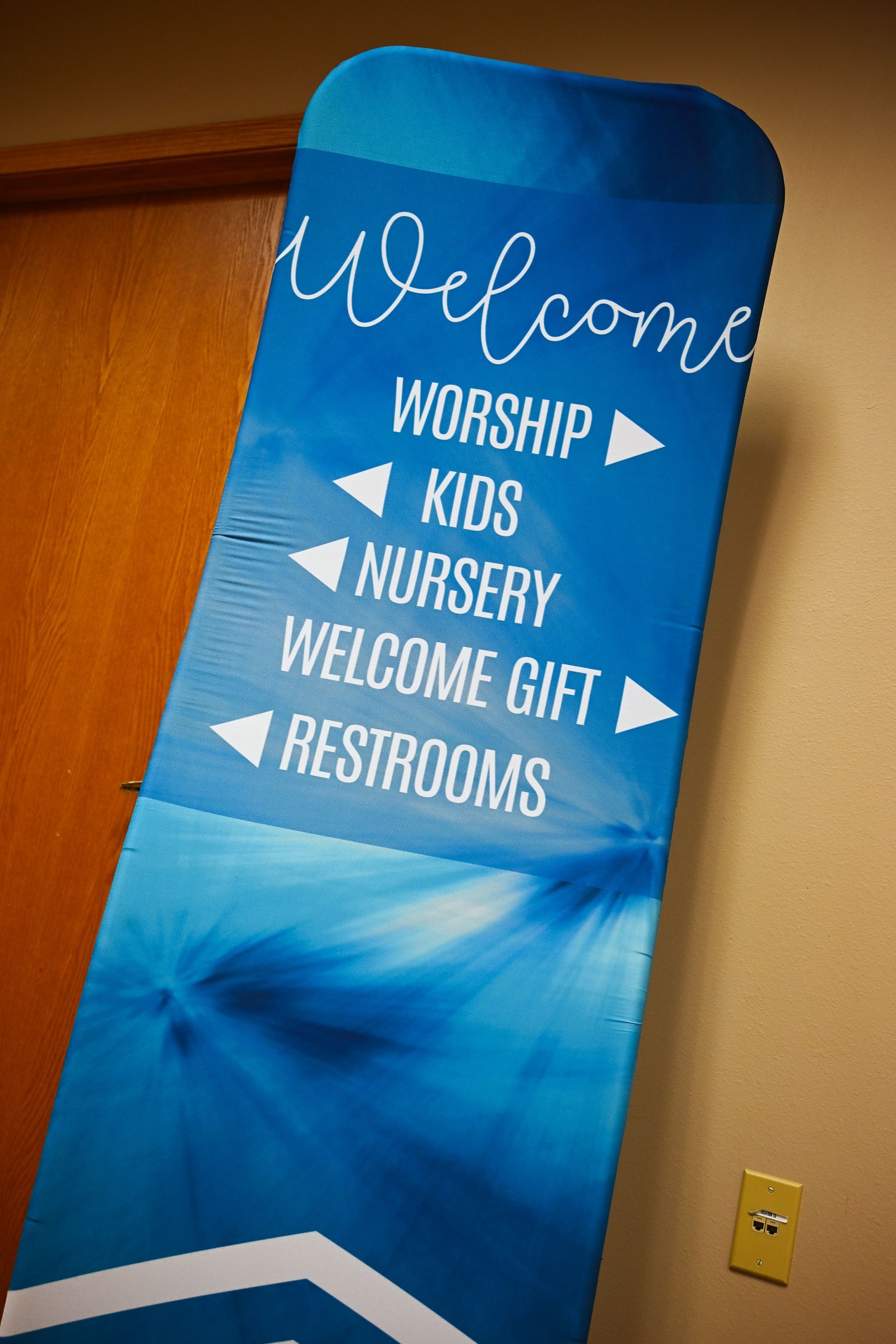 A blue sign that says welcome worship kids nursery welcome gift restrooms