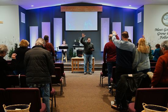 A group of people are sitting in a church with their hands in the air.