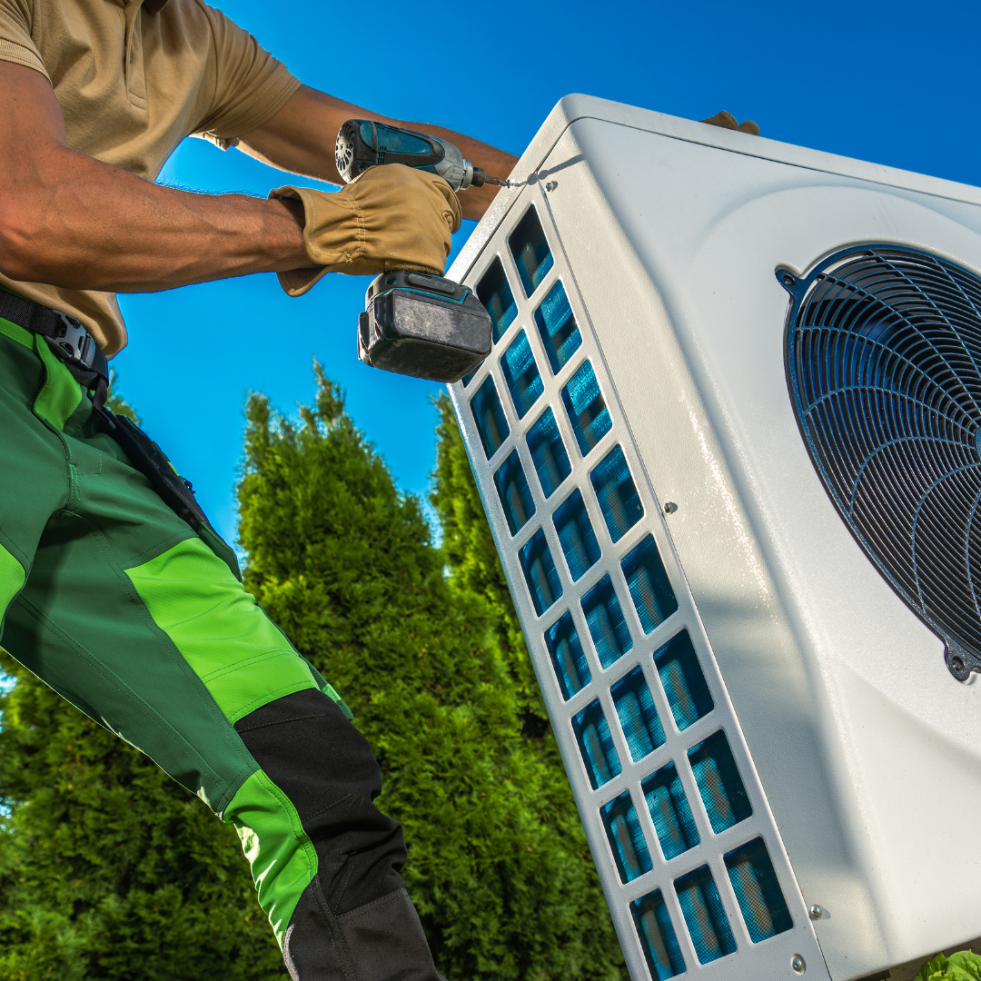 A man is working on an air conditioner with a drill.
