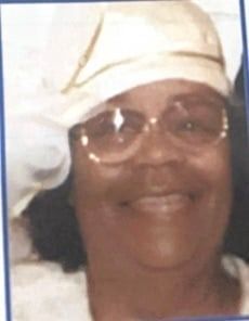 Woman wearing glasses and a white hat smiles.