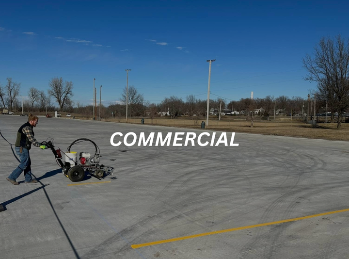 a man is using a machine to paint a yellow line on a parking lot .