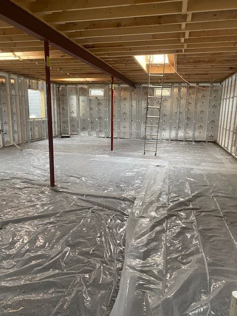 A basement under construction with a ladder in the corner