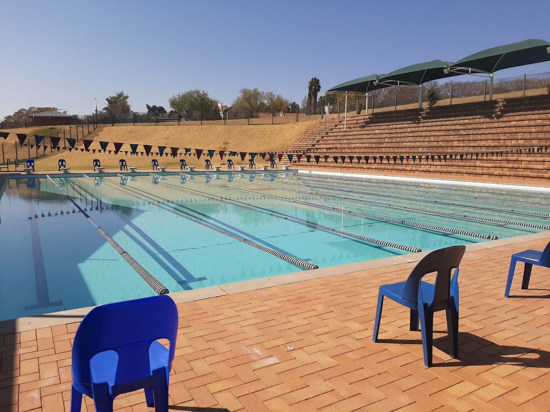 a swimming pool with blue chairs in front of it