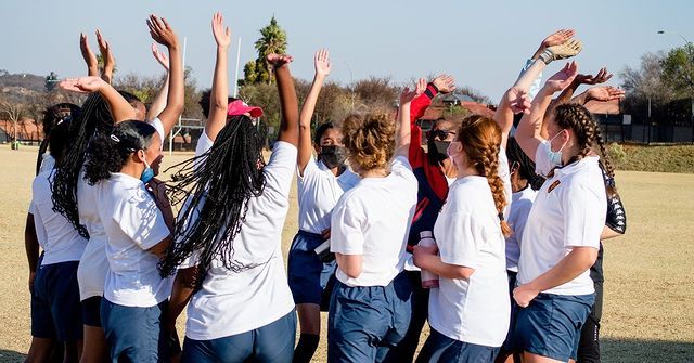 A group of young girls are standing in a circle with their hands in the air.