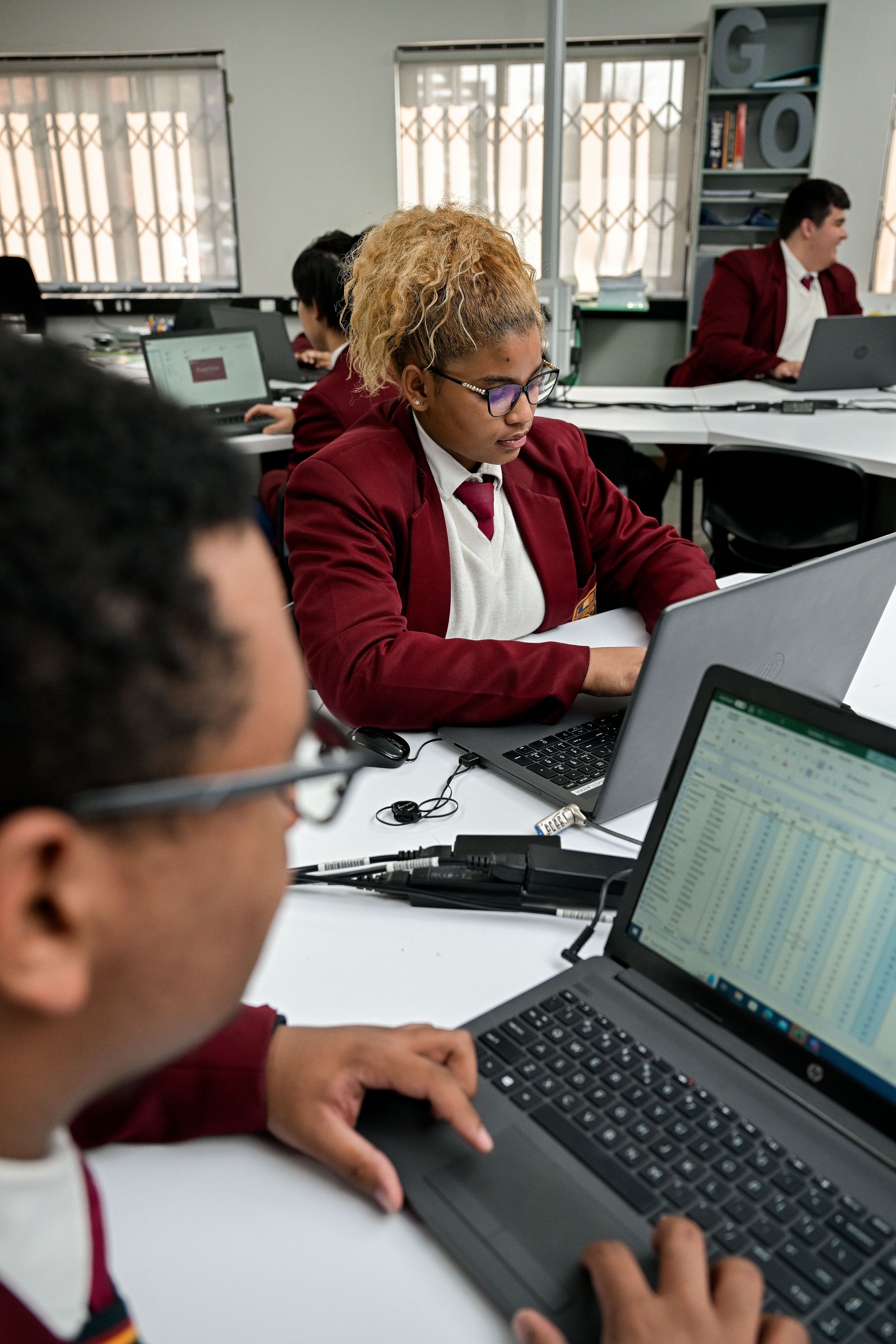 a boy in a white shirt and tie is using a screwdriver on a piece of paper .
