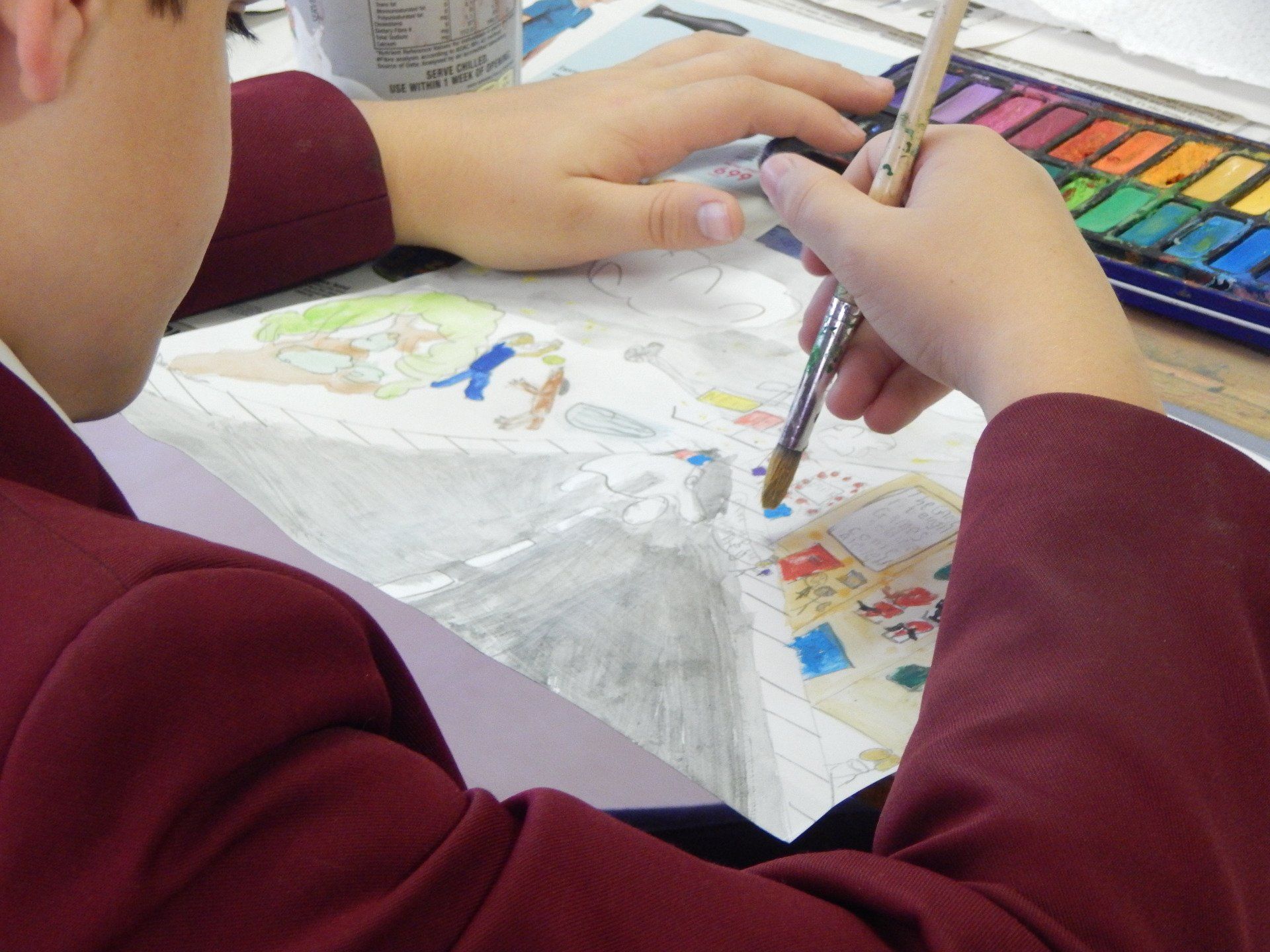 a child in a red jacket is painting with watercolors