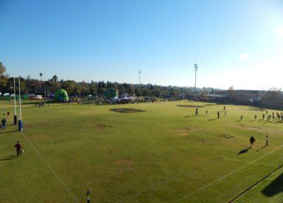 a group of students are playing rugby on a lush green field .