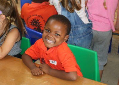 a young boy in an orange shirt is smiling at the camera