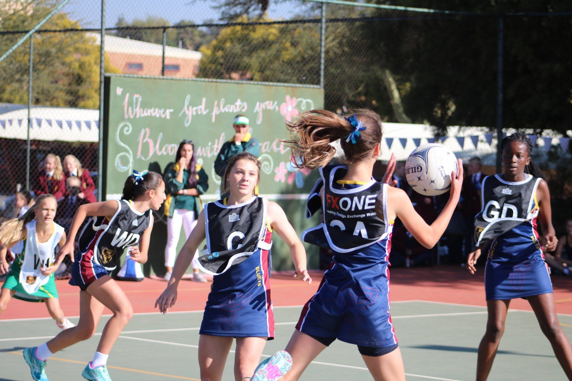 A group of young girls are playing a game of netball on a court.