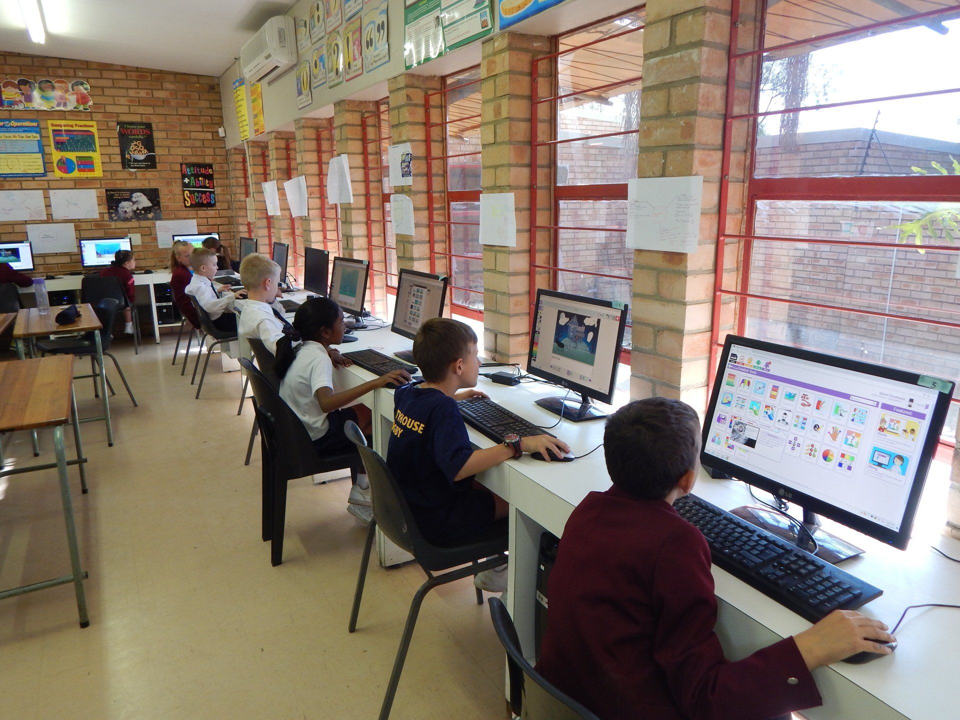 a group of children are sitting at computers in a classroom .