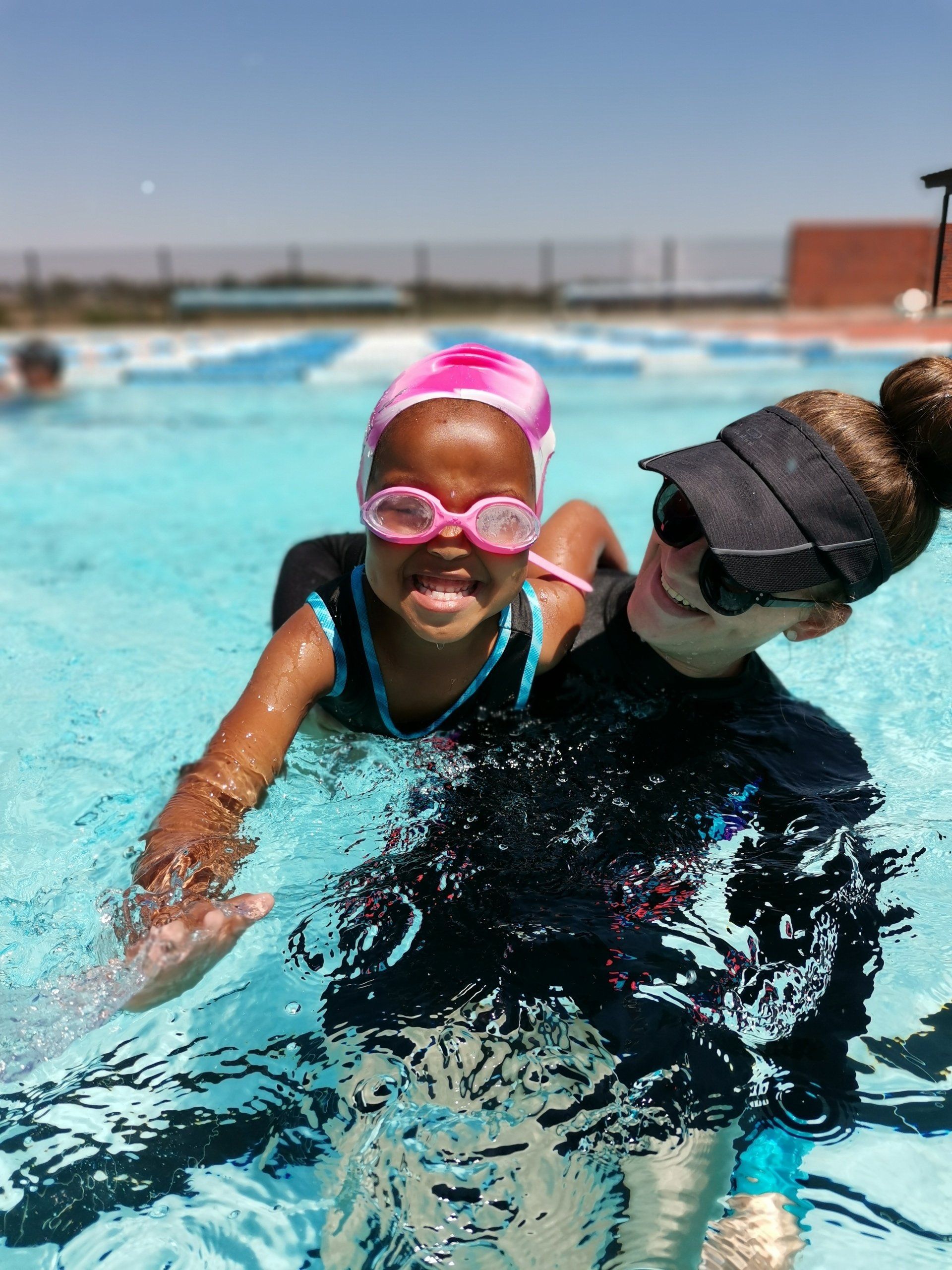 a woman is teaching a little girl how to swim in a pool
