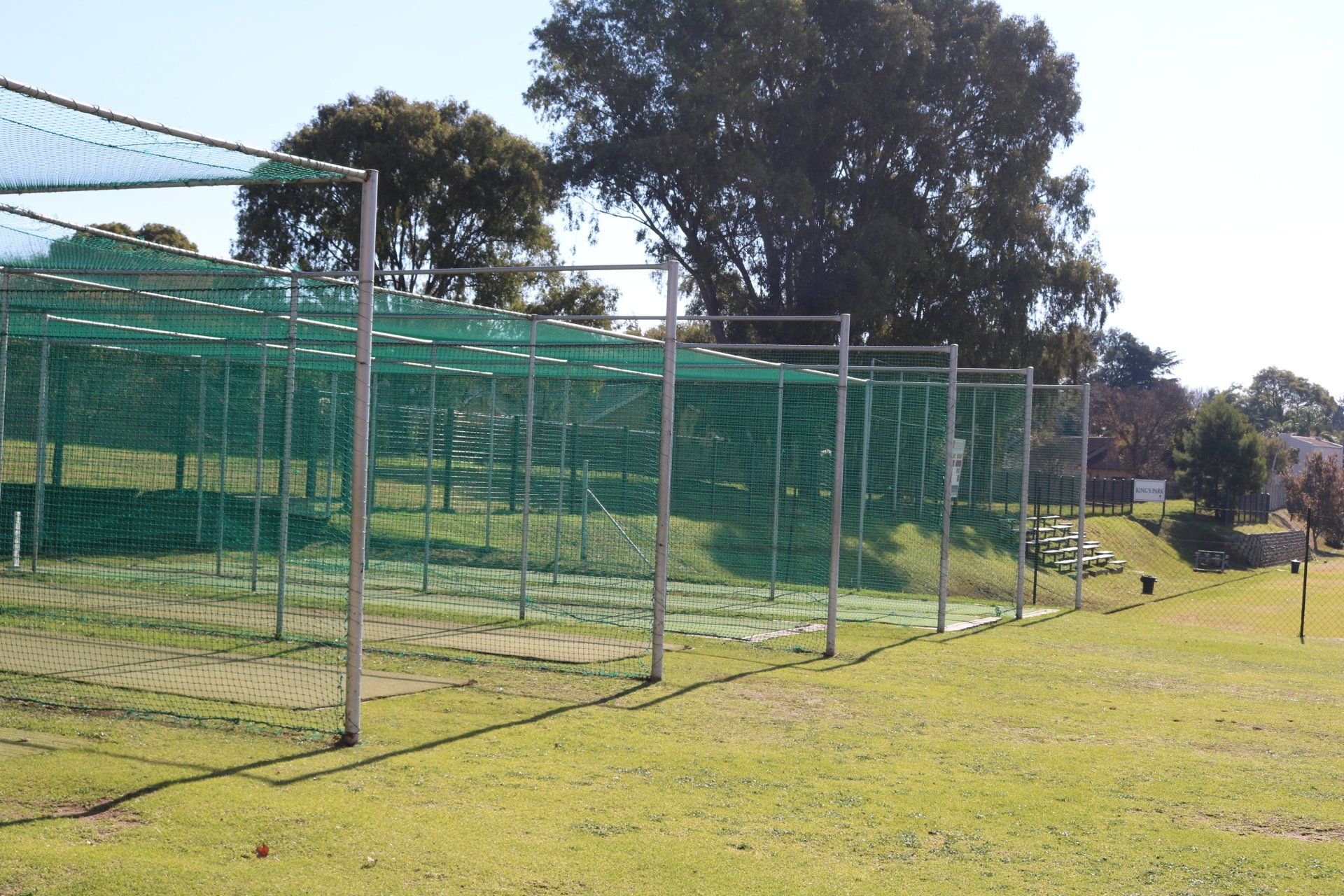 a cricket net in a field with trees in the background