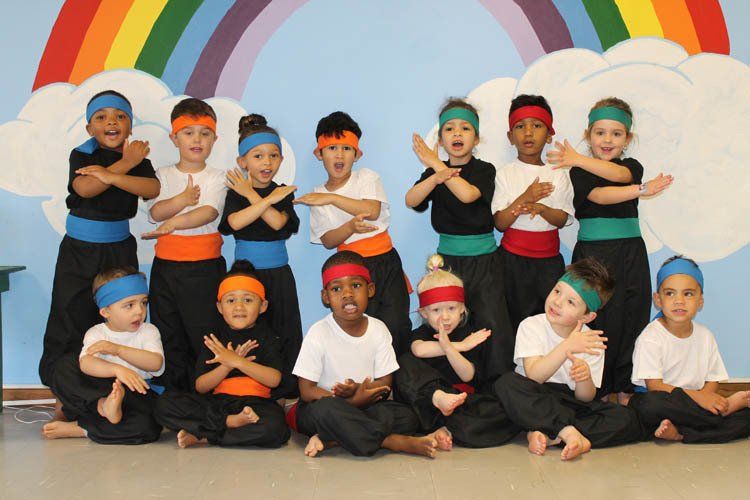 A group of children are posing for a picture in front of a rainbow