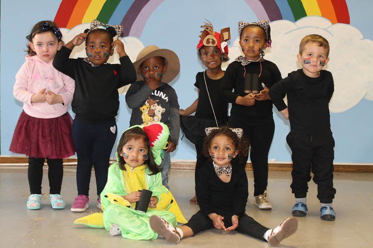 A group of children are posing for a picture with a rainbow in the background