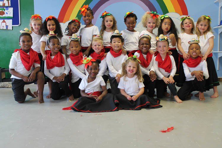 A group of children posing for a picture in front of a rainbow