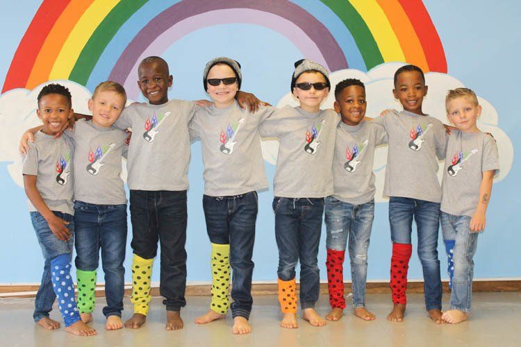 A group of children are posing for a picture in front of a rainbow