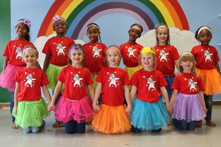 A group of young girls are posing for a picture in front of a rainbow