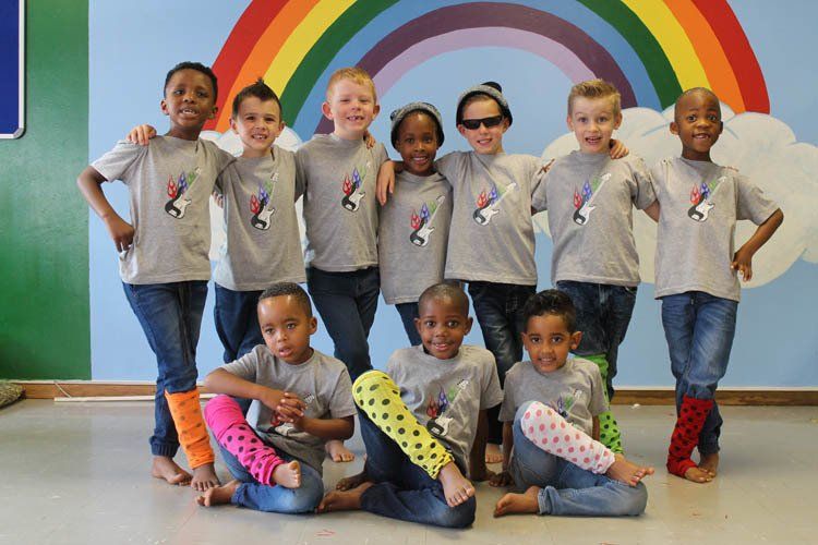 A group of children posing for a picture in front of a rainbow