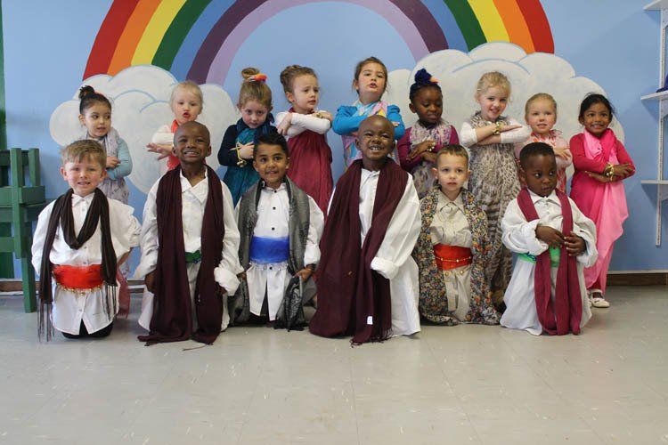 A group of children are posing for a picture in front of a rainbow.