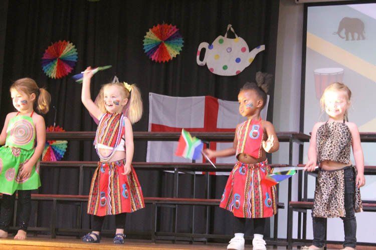 A group of young girls are standing on a stage wearing dresses with the number 8 on them
