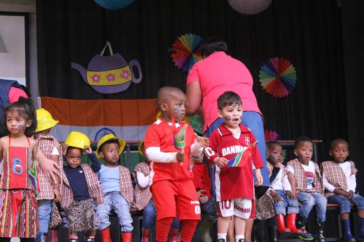 A group of children are standing on a stage and one of them is wearing a red shirt with the number 10 on it