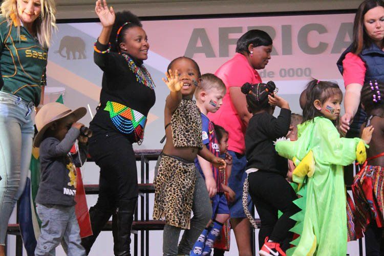A group of children are dancing in front of a sign that says africa