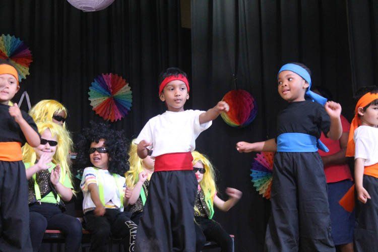 A group of young children are dancing on a stage