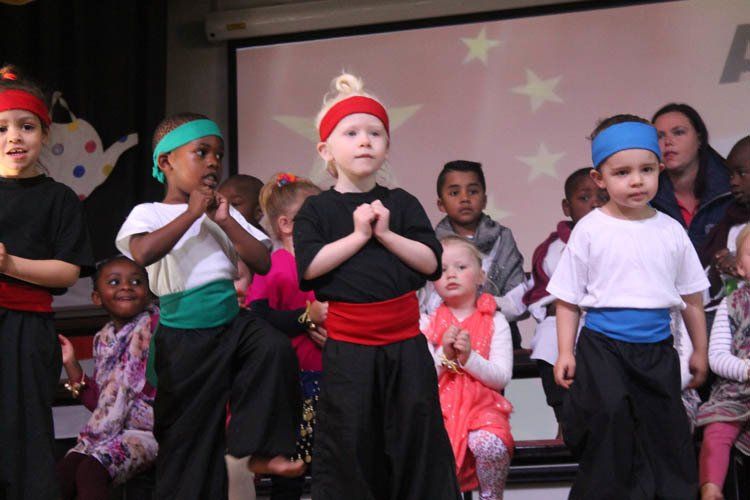 A group of children are dancing in front of a projector screen
