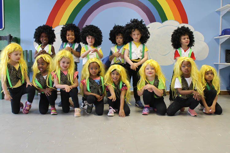 A group of children wearing yellow wigs are posing for a picture
