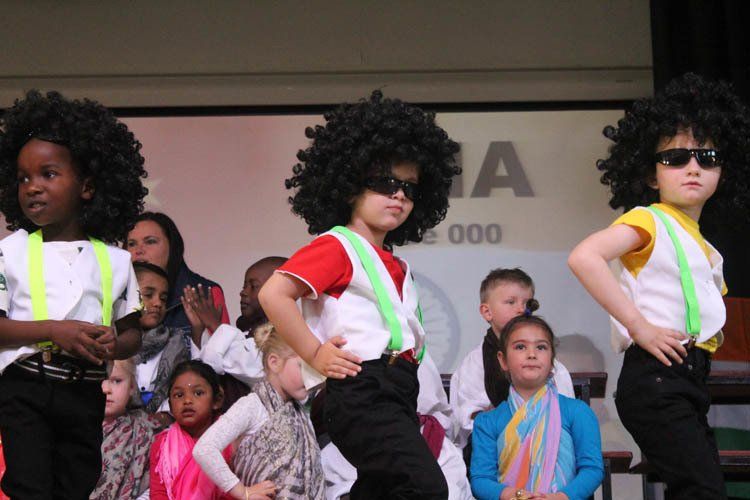 A group of children are dancing in front of a sign that says 000