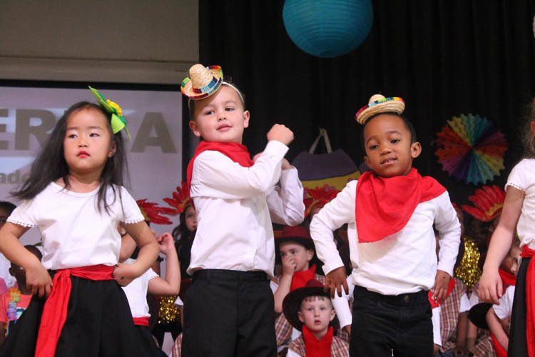 A group of children are dancing in front of a screen that says era