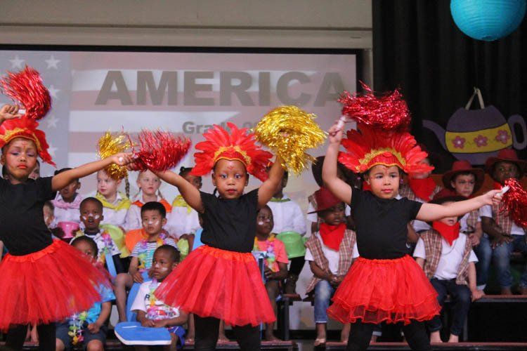 A group of children are dancing in front of a screen that says america