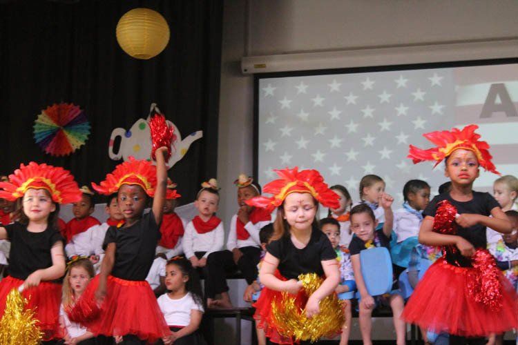 A group of children are dancing in front of a projector screen
