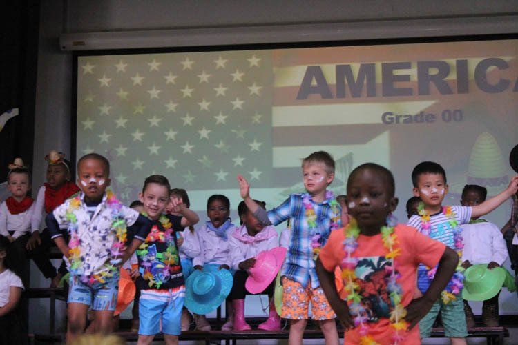 A group of children are dancing in front of a screen that says america