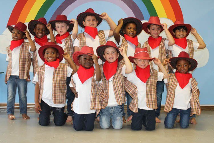A group of children wearing cowboy hats and scarves pose for a picture