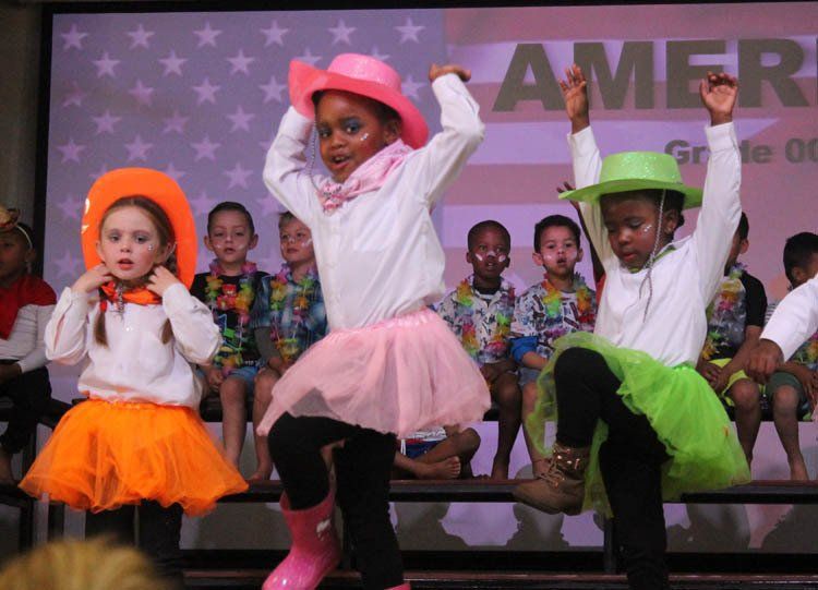 A group of children are dancing in front of an american flag