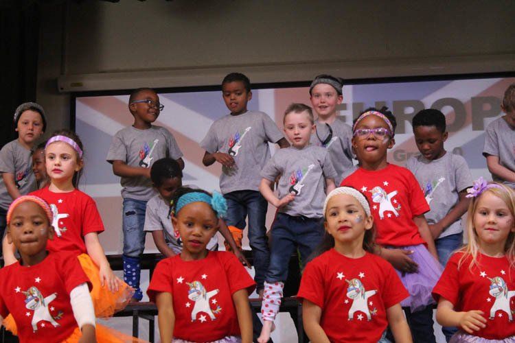 A group of children wearing red shirts with unicorns on them