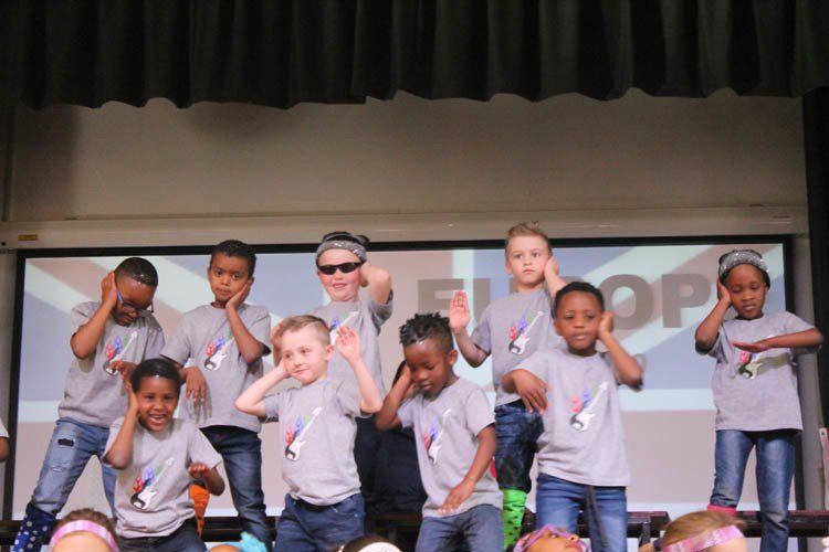 A group of children are dancing on a stage in front of a screen that says europe