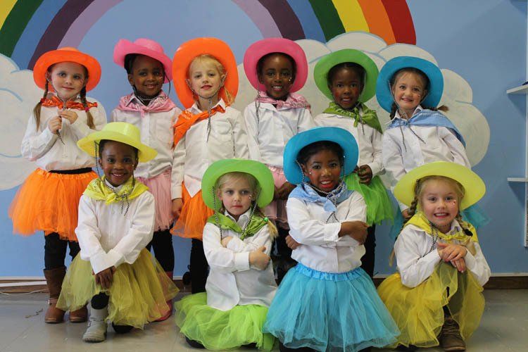 A group of young girls wearing cowboy hats and tutus are posing for a picture.