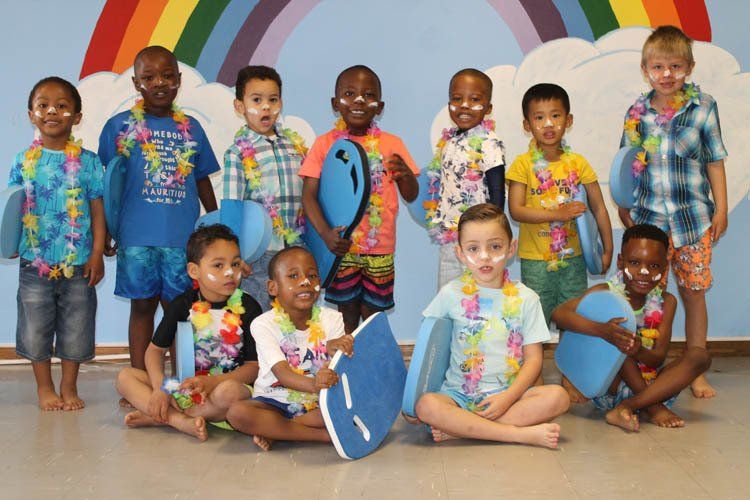 A group of children are posing for a picture in front of a rainbow