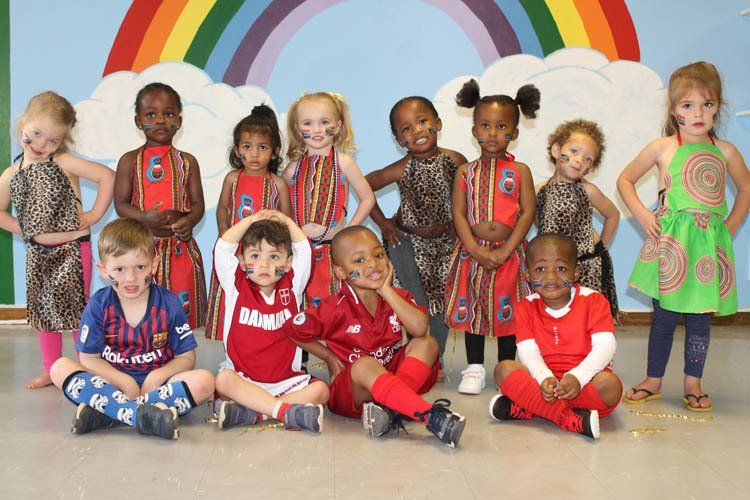 A group of children are posing for a picture in front of a rainbow