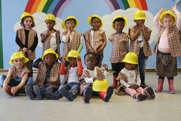 A group of children wearing hard hats are posing for a picture