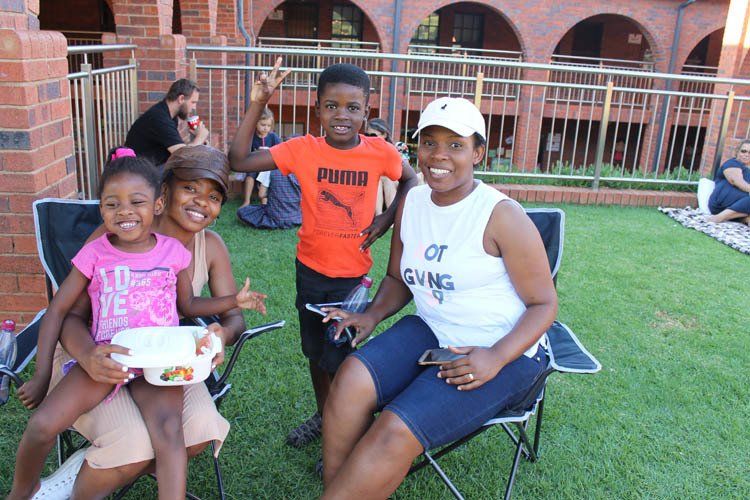 A woman is sitting in a chair with two children and a boy wearing an orange puma shirt