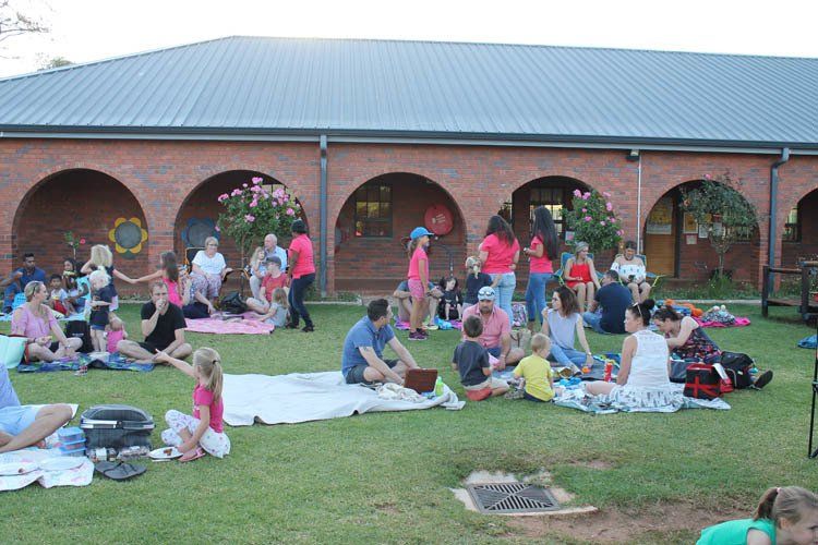 A group of people are sitting on the grass in front of a building.