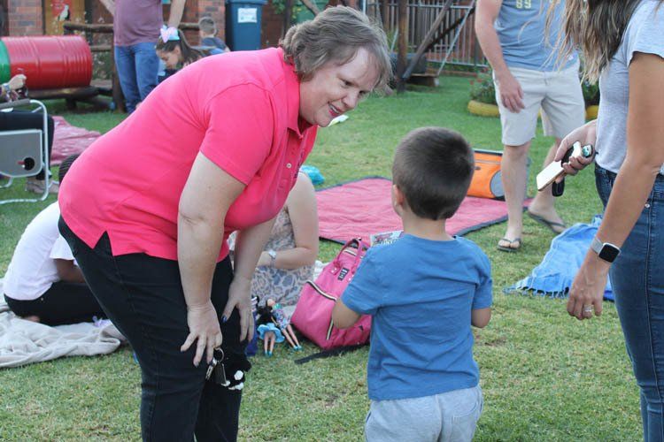 A woman in a pink shirt is talking to a little boy in a blue shirt.
