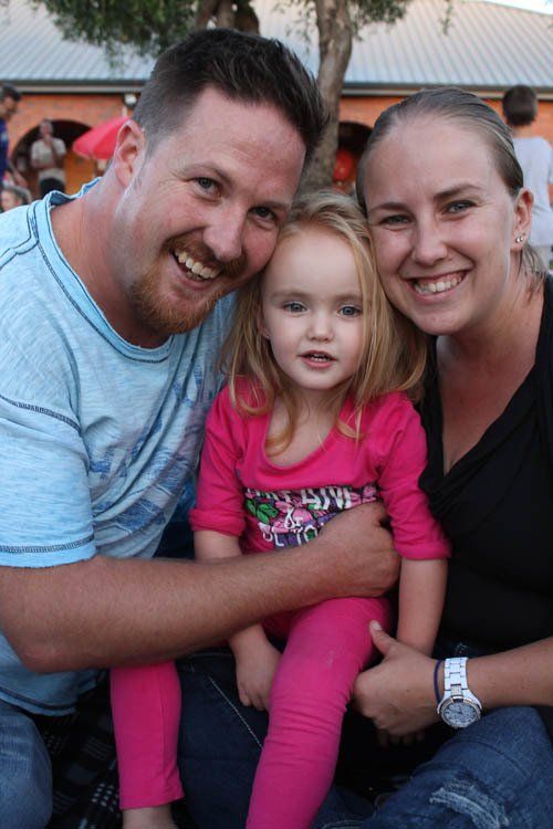 A man and woman are holding a little girl in their arms.